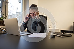 businessman working on laptop in office making phone call nervous and angry