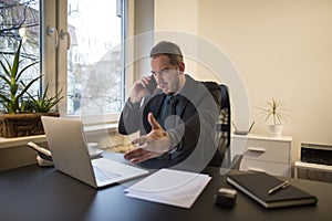 businessman working on laptop in office making phone call nervous and angry