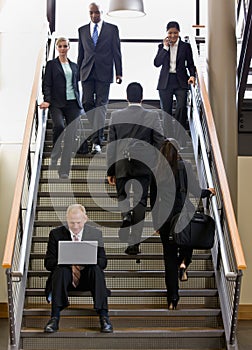 Businessman working on laptop on office stairs