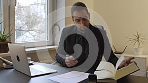 Businessman working on laptop in office taking notes