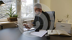 Businessman working on laptop in office taking notes and disappointed with results