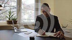 Businessman working on laptop in office taking notes making phone call satisfied with results