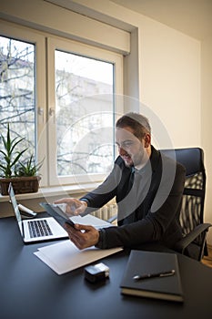 businessman working on laptop in office taking notes on tablet