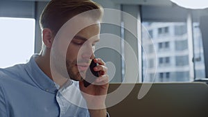 Businessman working on laptop in open space. Worker answering on phone call