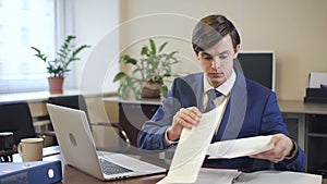 Businessman working on laptop and with paper document in modern office.