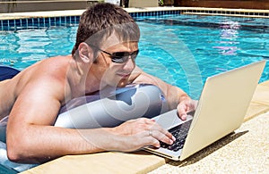 Businessman working with laptop in pool