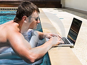 Businessman working with laptop in pool