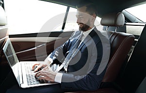 Businessman working with laptop sitting in car