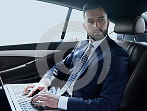 Businessman working with laptop sitting in car
