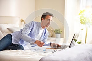 Businessman working with a laptop smiling lying on a bed photo