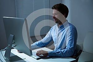 Businessman Working Late At Desk In Office