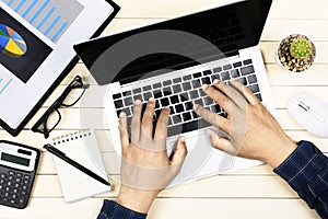 Businessman working with modern workplace with laptop on wood table, Man hand on laptop keyboard for work from home, Overhead view