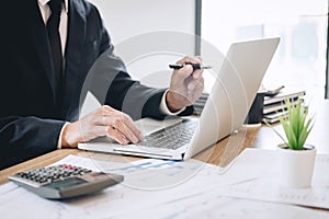 Businessman working new project on laptop computer with report document and analyze, calculating financial data on graph documents