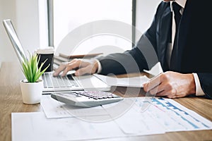 Businessman working new project on laptop computer with report document and analyze, calculating financial data on graph documents