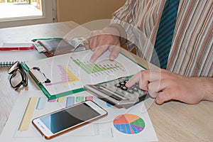 Businessman working on office desk with Calculator, a computer, a pen and document. Man, counting money