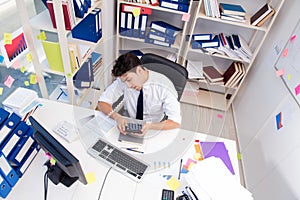 Businessman working in the office with piles of books and papers