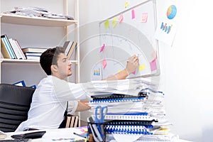 Businessman working in the office with piles of books and papers