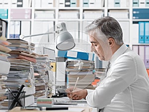 Businessman working in the office and piles of paperwork