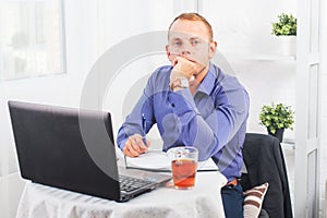 Businessman working in office, sitting at table with a laptop, looking camera