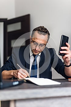 Businessman working in the office and use smartphone, documents on his desk