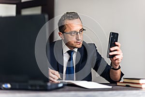 Businessman working in the office. He is using touchpad while reading an e-mail on laptop