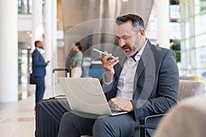 Businessman working with phone and laptop at the airport