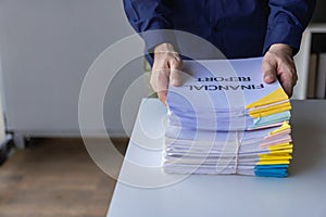 Businessman working in a pile of documents Find information about unfinished documents on the pile.