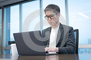 A businessman is working seriously with his laptop computer.