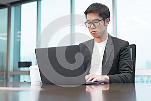 A businessman is working seriously with his laptop computer.