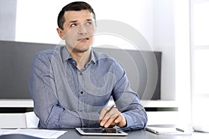 Businessman working with tablet computer in modern office. Headshot of male entrepreneur or company director at