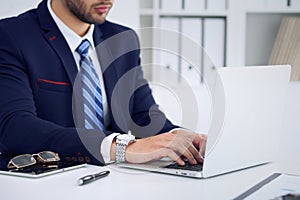 Businessman working by typing on laptop computer. Man`s hands on notebook or business person at workplace. Employment o