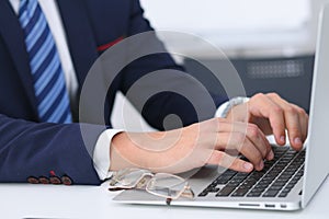 Businessman working by typing on laptop computer. Man`s hands on notebook or business person at workplace. Employment o