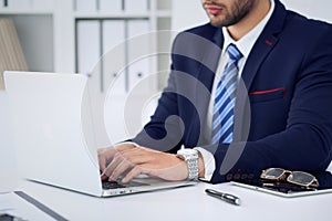 Businessman working by typing on laptop computer. Man`s hands on notebook or business person at workplace. Employment o