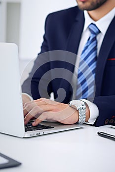 Businessman working by typing on laptop computer. Man`s hands on notebook or business person at workplace. Employment o