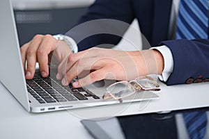 Businessman working by typing on laptop computer. Man`s hands on notebook or business person at workplace. Employment o