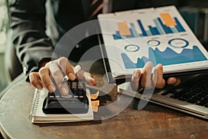 Businessman working using a calculator to calculate and chart the numbers of static in office. Finance accounting concept