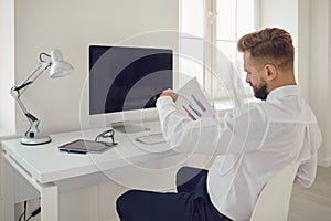 Businessman works at a table with a computer in the office. Back view.