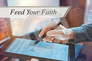 A businessman works with a tablet. The inscription Feed Your Faith