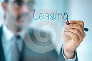 Businessman write the word Leasing and give a brief property, buildings, vehicles are common assets that are leased.