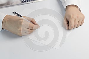 Businessman writes on a sheet of white paper. Dressed in a shirt and tie. Close-up photo