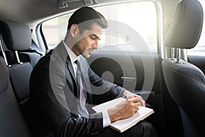 Businessman Writing In Diary In Car