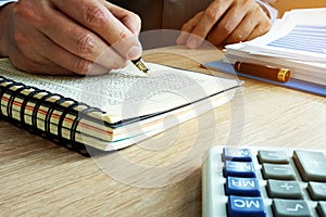 Businessman writing financial results in book. Bookkeeping concept.