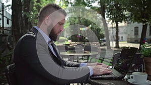 Businessman writing on laptop, outdoor. Steadicam shot.