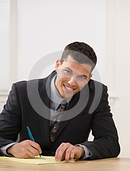 Businessman writing on legal pad taking notes