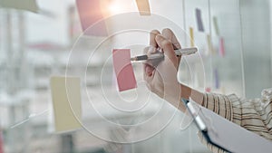 Businessman writing new idea on sticky notes at bright office.