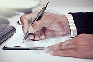 Businessman writing on notebook with pen in the office