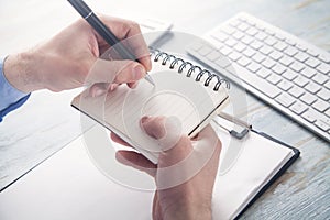 Businessman writing on notepad in business desk