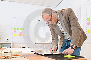 Businessman Writing On Notepad At Desk