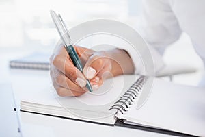 Businessman writing in notepad at desk