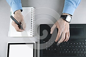 Businessman writing on notepad and using laptop. Business concept